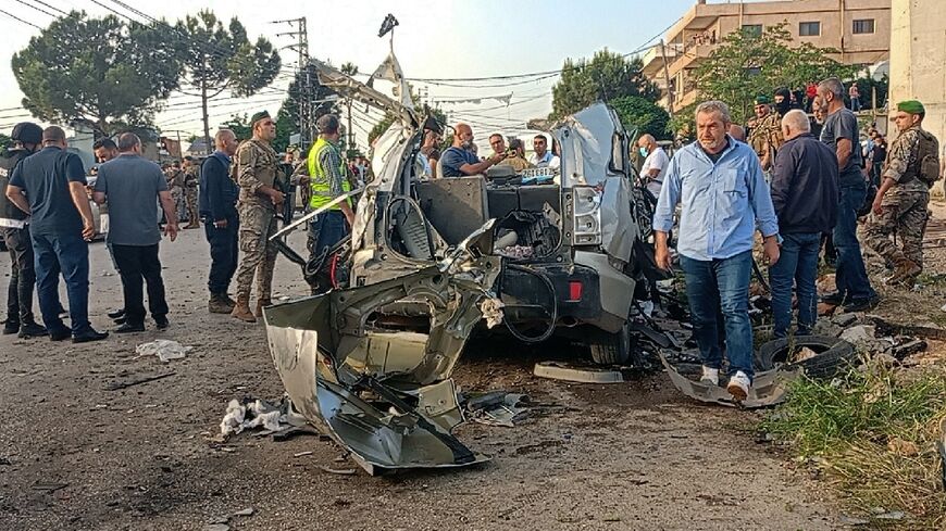 Lebanese soldiers and onlookers gather around the remnants of a car after it was hit by an Israeli strike, reportedly killing a Hamas commander, in Lebanon's Bekaa Valley